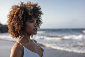 Portrait of beautiful young African woman in white dress with beach background.